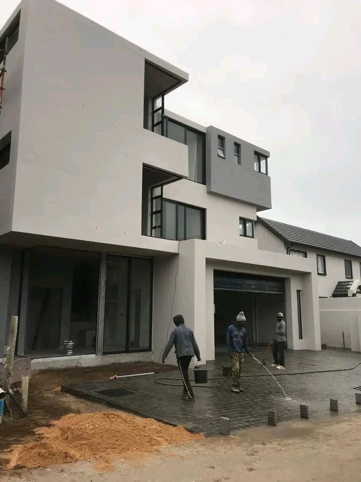 Modern multi-storey house under construction in Cape Town with a worker on site