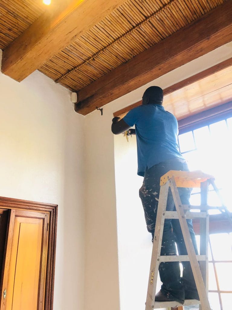 Painter on a ladder painting an interior wall in a Cape Town home