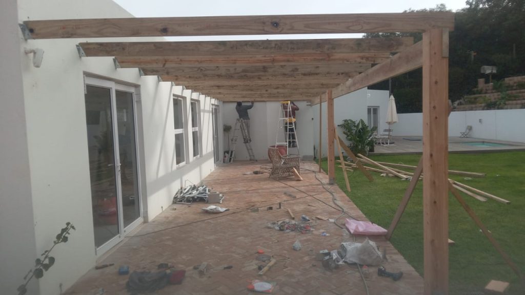 Timber pergola frame being built over a patio at a white Cape Town home