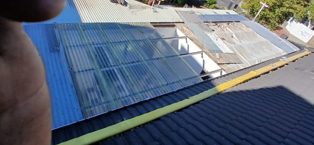 Worker applying waterproofing material to a metal roof