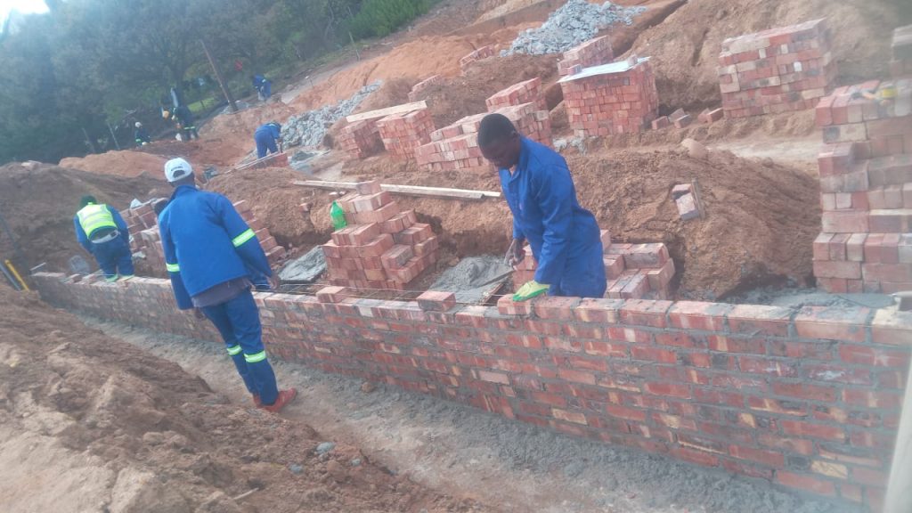 Builder carrying bricks on a foundation site in Cape Town