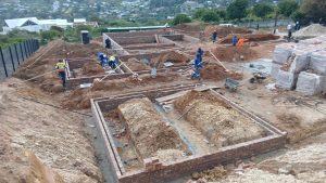 Building team working on brick foundations on a sloping site