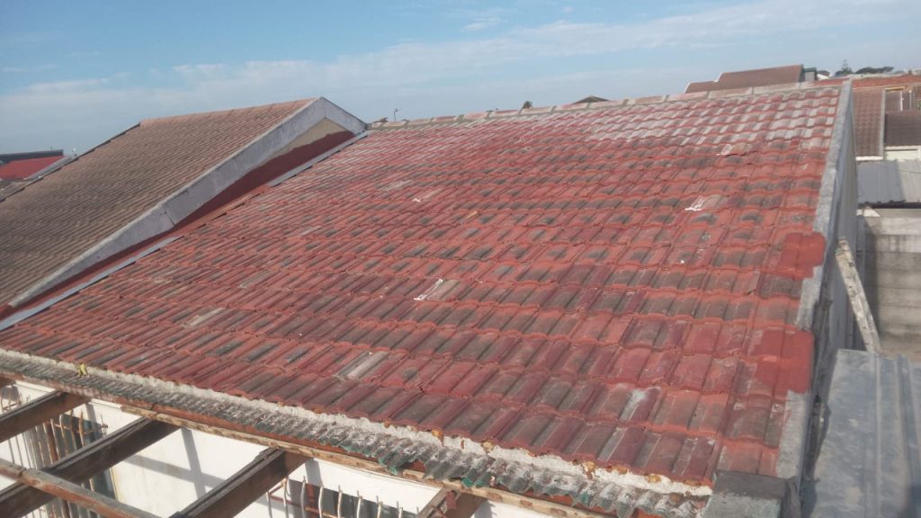Weathered red tiled roof on a Cape home before repair
