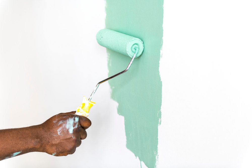 Paint roller applying mint-green paint to a wall